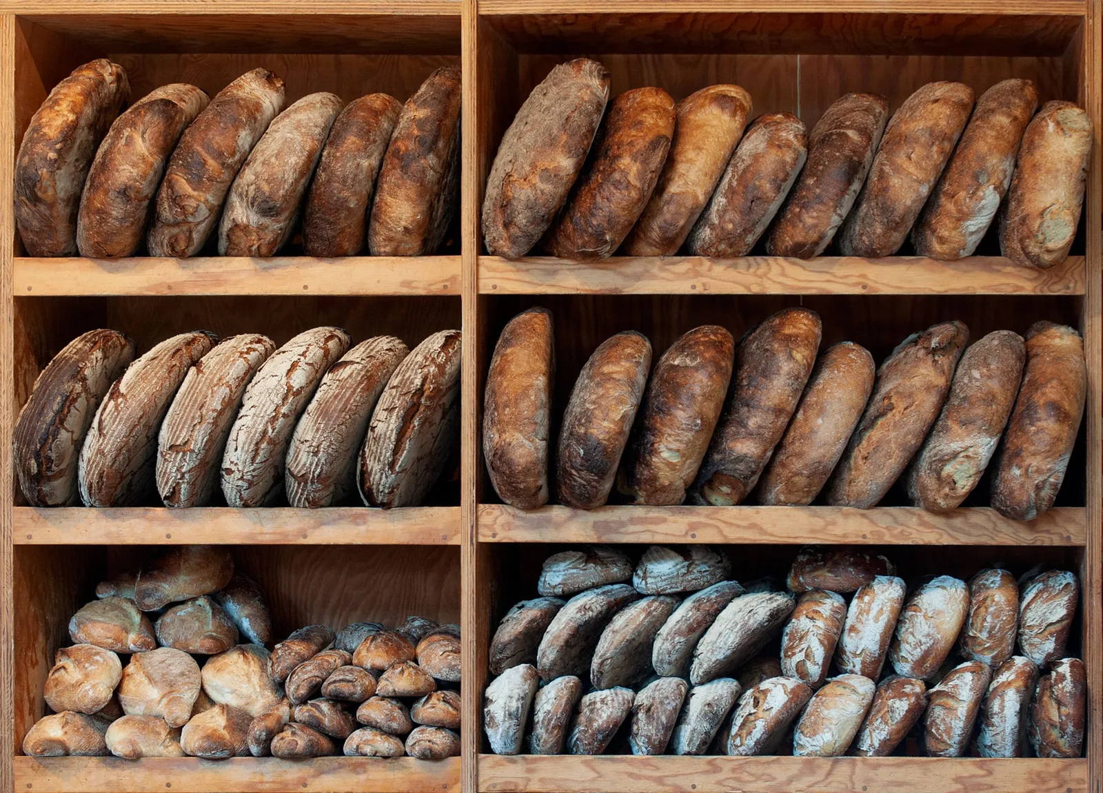 Rustic loaves standing in rows on wooden bakery shelves