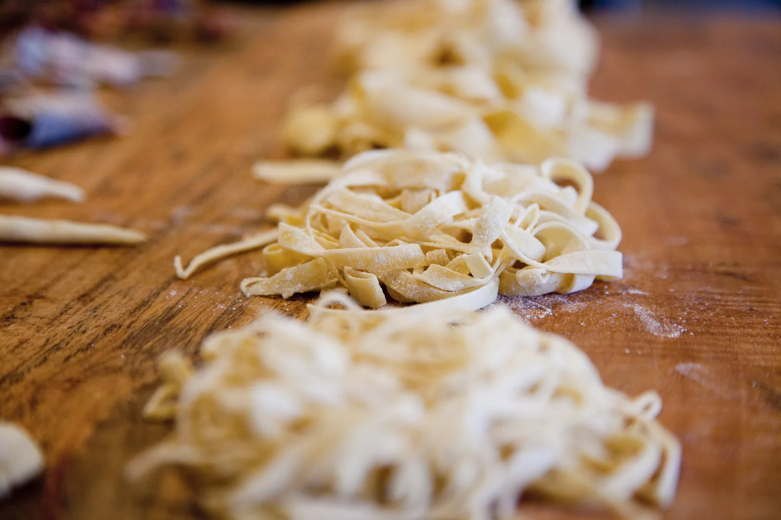 Nests of fresh pasta on a floured wooden table